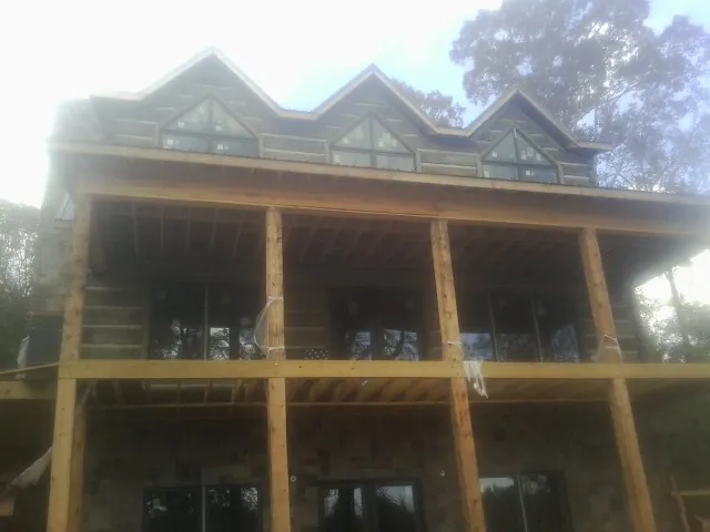 Dormers and porch framing on a large log home under construction — Roof Coating work by our crew in Powellsville
