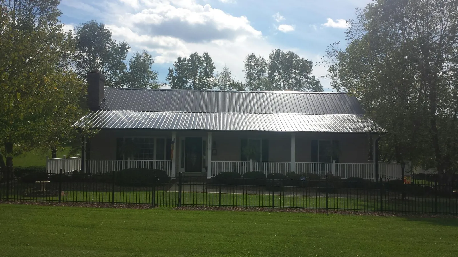 Gray metal roof on a brick ranch with a full width front porch — Gutter Guard Installation work by our crew in Powellsville