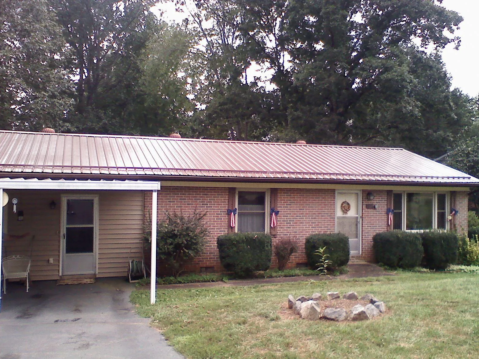 Bronze metal roof and carport on a brick ranch home — Roof Repair work by our crew in Powellsville