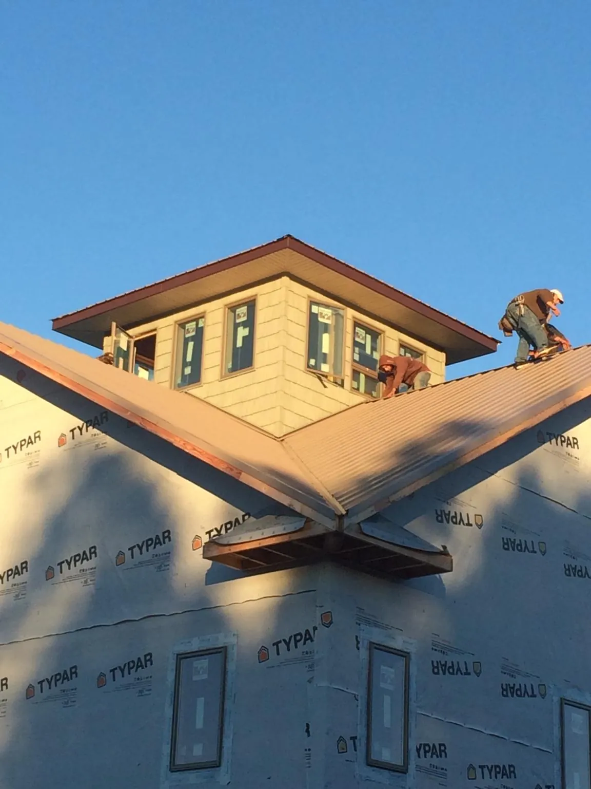 Roofers working around a rooftop cupola on a new metal roof at sunset — Roof Waterproofing in Powellsville by Roofing Brothers